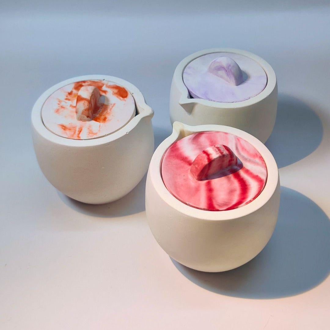 This image displays a set of three Spout Jar + Jar Lid products. Each jar is uniquely colored—one with a vibrant pink content, another with a deep blue, and the third appears to have a natural beige tone.